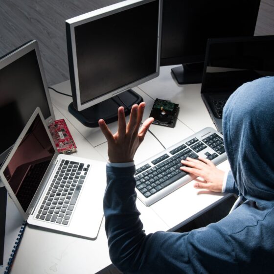 A mysterious figure shown working on multiple desktop pc's
