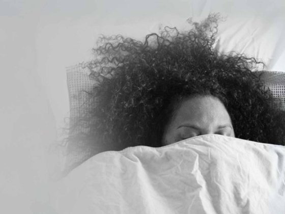 A woman in bed with the blankets pulled up around her face